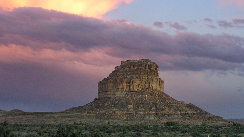 A tall weathered stone butte under sunset clouds