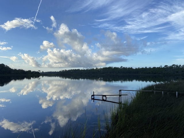 scenic view of silhouetted landscape and blues sky and clouds reflected in water