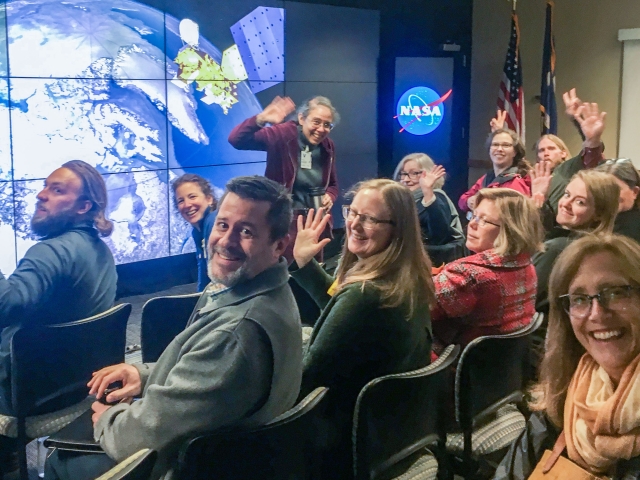 Group of new regional leaders waves at the camera in front of satellite image of Earth
