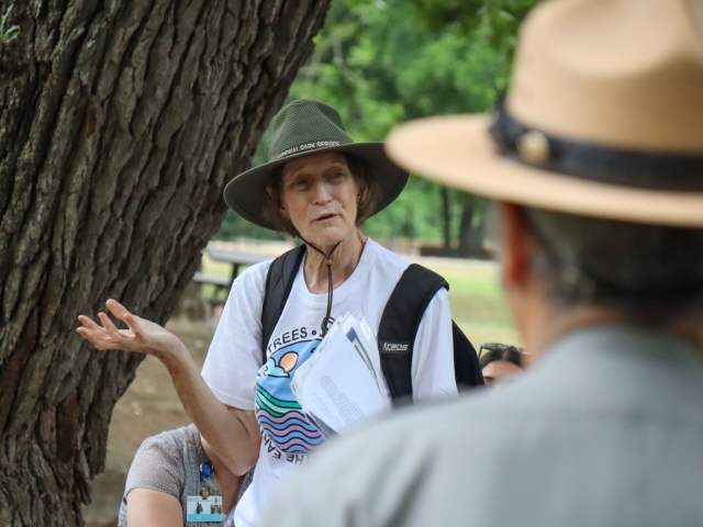 Woman gestures during outdoors presentation to park ranger